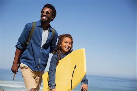 Smiling father and daughter with boogie board on sunny summer ocean beach Stock Photo - Premium Royalty-Free, Code: 6113-09027718