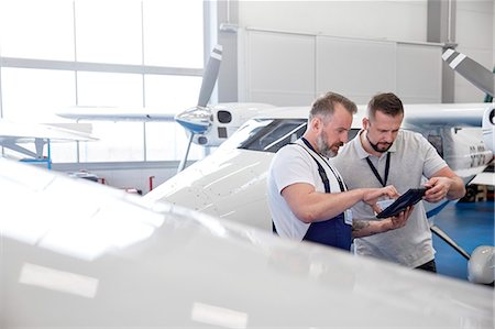 Male mechanic engineers using digital tablet near airplane in hangar Stock Photo - Premium Royalty-Free, Code: 6113-09027818