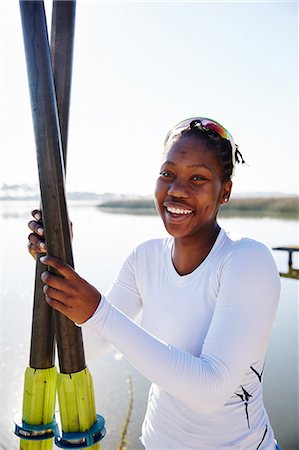 Portrait smiling, confident female rower holding oars at sunny lakeside Stock Photo - Premium Royalty-Free, Code: 6113-09144522