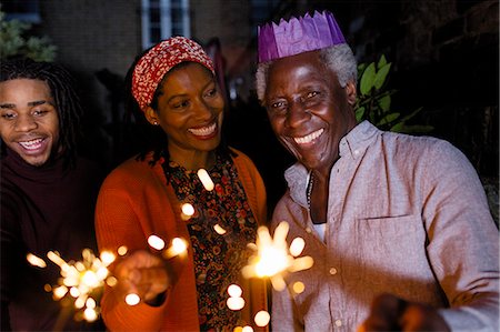 Portrait smiling senior father with sparklers in paper crown celebrating with daughter Stock Photo - Premium Royalty-Free, Code: 6113-09144657