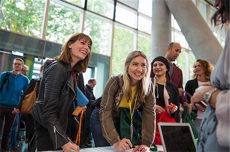 simsearch:6113-09157438,k - Smiling businesswomen arriving, checking in at conference registration table Photographie de stock - Premium Libres de Droits, Code: 6113-09157548