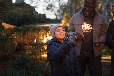 senior winter adult family - Smiling grandson and grandfather playing with firework sparklers Stock Photo - Premium Royalty-Free, Code: 6113-09157615