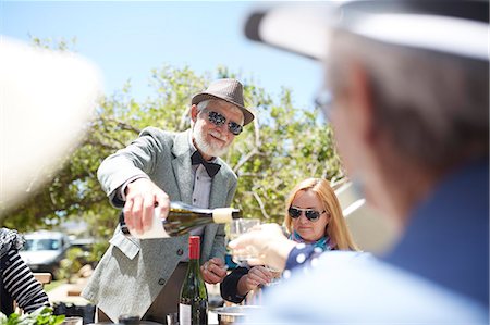 simsearch:632-05816053,k - Senior man in suit and bow tie pouring wine for friends at sunny garden party Foto de stock - Sin royalties Premium, Código: 6113-09157720