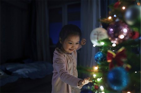 simsearch:6113-08521307,k - Curious, cute girl touching illuminated Christmas tree Fotografie stock - Premium Royalty-Free, Codice: 6113-09157943