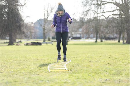Woman doing speed ladder drill in sunny park Stock Photo - Premium Royalty-Free, Code: 6113-09160167