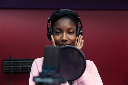 Portrait confident teenage girl musician recording music, singing in sound booth Stock Photo - Premium Royalty-Free, Code: 6113-09168267