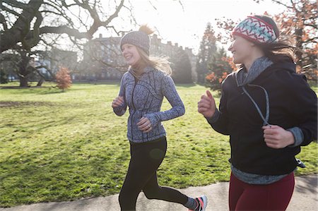 simsearch:6113-09168318,k - Smiling female runners running in sunny park Foto de stock - Royalty Free Premium, Número: 6113-09168320