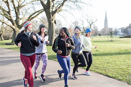 simsearch:6113-09168318,k - Smiling female runners running in sunny park Foto de stock - Royalty Free Premium, Número: 6113-09168330