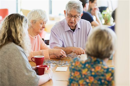 senior woman drinking coffee - Senior friends assembling jigsaw puzzle and drinking tea at table in community center Stock Photo - Premium Royalty-Free, Code: 6113-09168400