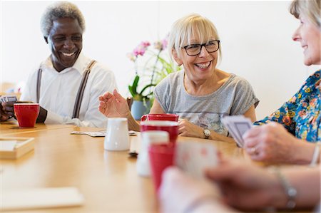 simsearch:6122-07697873,k - Happy senior friends playing cards at tale in community center Stock Photo - Premium Royalty-Free, Code: 6113-09168404