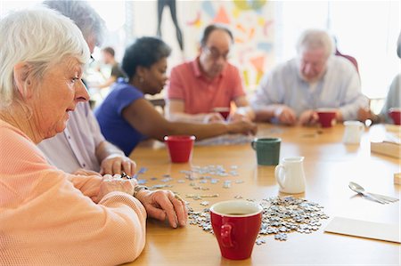 simsearch:6113-07146829,k - Senior woman assembling jigsaw puzzle with friends at table in community center Foto de stock - Sin royalties Premium, Código: 6113-09168411