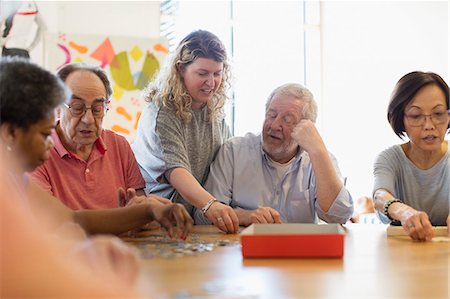 people holding puzzle pieces - Volunteer helping senior man assembling jigsaw puzzle at table in community center Stock Photo - Premium Royalty-Free, Code: 6113-09168423