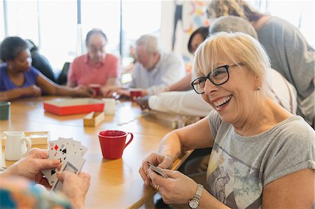 retirement community - Happy senior woman playing cards with friend at table in community center Stock Photo - Premium Royalty-Free, Code: 6113-09168426
