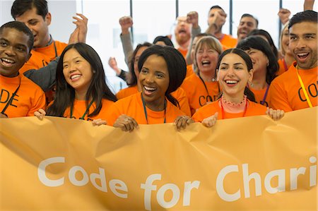 Happy hackers with banner coding for charity at hackathon Stock Photo - Premium Royalty-Free, Code: 6113-09168661