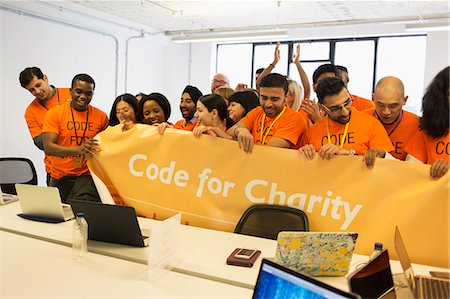 Hackers with banner coding for charity at hackathon Stock Photo - Premium Royalty-Free, Code: 6113-09168617