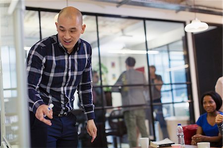 entrepreneur candid - Businessman leading meeting, pointing to whiteboard Stock Photo - Premium Royalty-Free, Code: 6113-09168771