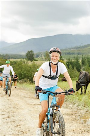 simsearch:6113-09168871,k - Smiling, confident mature man mountain biking on rural dirt road Stock Photo - Premium Royalty-Free, Code: 6113-09168882