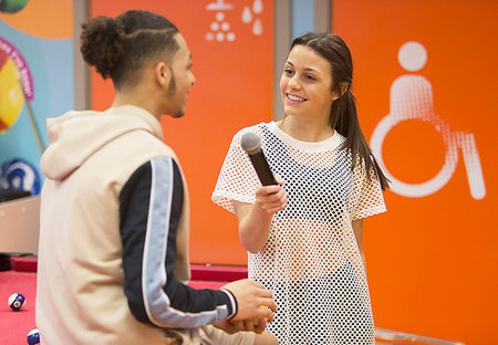 Teenage girl with microphone interviewing boy Stock Photo - Premium Royalty-Free, Code: 6113-09178542