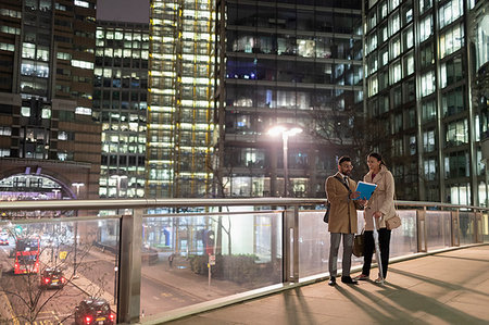Business people discussing paperwork on urban pedestrian bridge at night Stock Photo - Premium Royalty-Free, Code: 6113-09178792