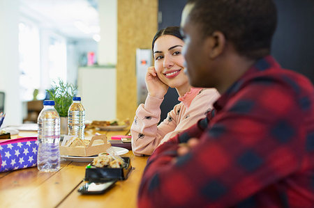 Smiling businesswoman listening to businessman, eating lunch in office Stock Photo - Premium Royalty-Free, Code: 6113-09178727