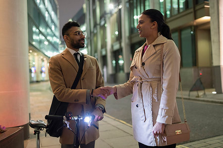Business people with bicycle handshaking on urban sidewalk at night Stock Photo - Premium Royalty-Free, Code: 6113-09178846