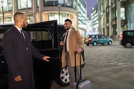 Driver opening car door for businessman with suitcase on urban street at night Foto de stock - Sin royalties Premium, Código: 6113-09178848