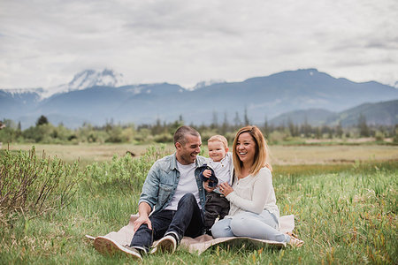 Parents and baby son sitting in rural field with mountains in background Stock Photo - Premium Royalty-Free, Code: 6113-09178872