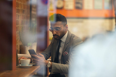 simsearch:6108-05874440,k - Businessman using smart phone, working in cafe Stock Photo - Premium Royalty-Free, Code: 6113-09178800