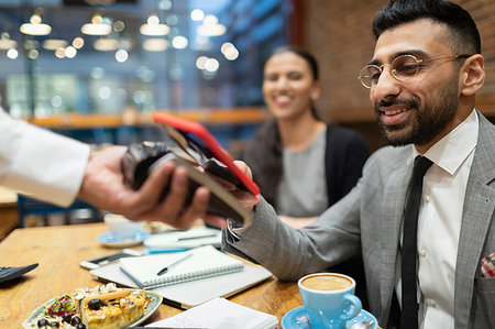 Businessman paying with smart phone contactless payment in cafe Foto de stock - Sin royalties Premium, Código: 6113-09178821