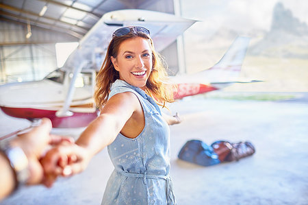 Personal perspective eager woman leading man by the hand toward small airplane Stock Photo - Premium Royalty-Free, Code: 6113-09179040
