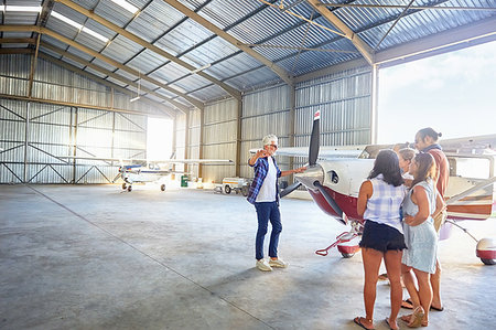 simsearch:6113-09179045,k - Pilot talking to friends at prop airplane in airplane hangar Foto de stock - Sin royalties Premium, Código: 6113-09179042