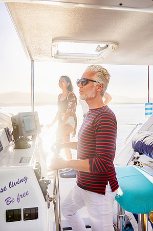 simsearch:6113-09179043,k - Man at helm on sunny boat Stock Photo - Premium Royalty-Free, Code: 6113-09179001