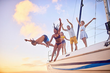 simsearch:6113-09179023,k - Playful friends jumping off boat Photographie de stock - Premium Libres de Droits, Code: 6113-09179015