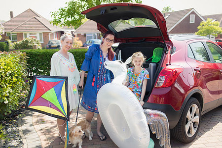 family portrait daughter dog - Portrait lesbian couple and daughter with kite and inflatable unicorn loading car in driveway Stock Photo - Premium Royalty-Free, Code: 6113-09191918