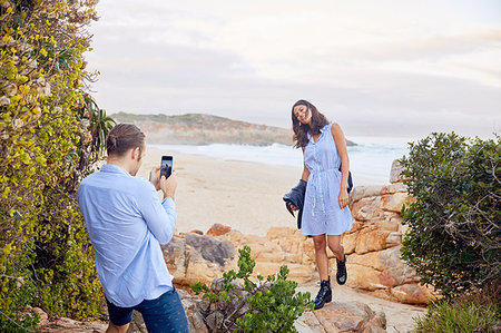 simsearch:6113-08910121,k - Young man with smart phone photographing girlfriend with ocean in background Photographie de stock - Premium Libres de Droits, Code: 6113-09192066