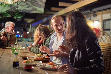 Couple eating, enjoying sushi on patio at night Stock Photo - Premium Royalty-Free, Code: 6113-09192084
