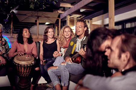 Friends hanging out, playing music on patio at night Stock Photo - Premium Royalty-Free, Code: 6113-09192093