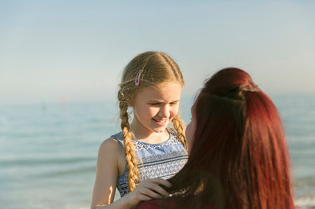 Affectionate mother holding daughter on sunny ocean beach Stock Photo - Premium Royalty-Free, Code: 6113-09199752