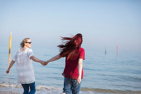 simsearch:6113-09199766,k - Affectionate lesbian couple holding hands on sunny ocean beach Fotografie stock - Premium Royalty-Free, Codice: 6113-09199755