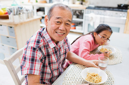 simsearch:6113-06908828,k - Portrait smiling grandfather eating noodles with granddaughter at table Stock Photo - Premium Royalty-Free, Code: 6113-09199892