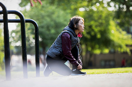 Active senior female runner with headphones tying shoe in park Stock Photo - Premium Royalty-Free, Code: 6113-09199821