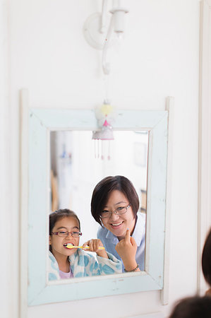 Mother watching daughter brushing teeth in bathroom mirror Stock Photo - Premium Royalty-Free, Code: 6113-09199982