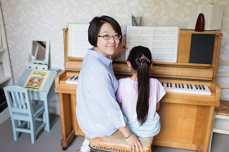 Portrait smiling mother sitting with daughter playing piano Stock Photo - Premium Royalty-Free, Code: 6113-09199920