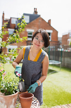 simsearch:400-08252596,k - Portrait smiling woman gardening, potting flowers in sunny yard Photographie de stock - Premium Libres de Droits, Code: 6113-09199936