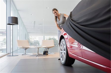 simsearch:6113-09111784,k - Car saleswoman removing cover from new car in car dealership showroom Photographie de stock - Premium Libres de Droits, Code: 6113-09111752