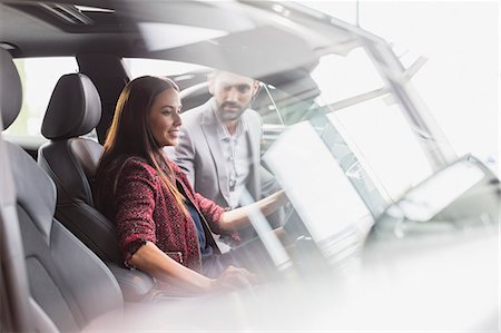 simsearch:6113-09111753,k - Car salesman and female customer in driver's seat of new car in car dealership showroom Stock Photo - Premium Royalty-Free, Code: 6113-09111759