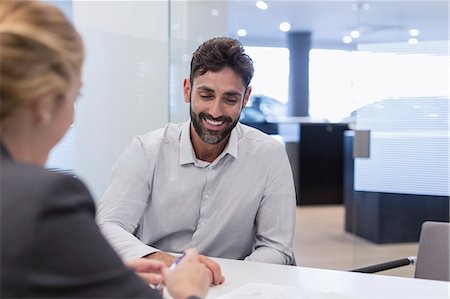 simsearch:6113-09111784,k - Smiling male customer listening to car saleswoman in car dealership office Stock Photo - Premium Royalty-Free, Code: 6113-09111769