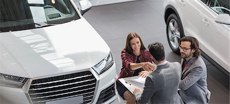 Car salesman shaking hands with female customer in car dealership showroom Foto de stock - Sin royalties Premium, Código: 6113-09111856