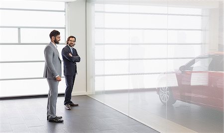 Car salesman and male customer looking at new car in car dealership showroom Photographie de stock - Premium Libres de Droits, Code: 6113-09111829