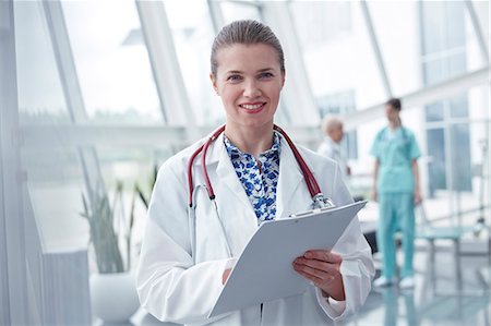 simsearch:6113-09111906,k - Portrait smiling, confident female doctor with clipboard in hospital Foto de stock - Sin royalties Premium, Código: 6113-09111942